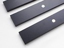 Close-up of three black flat metal bars with central circular holes