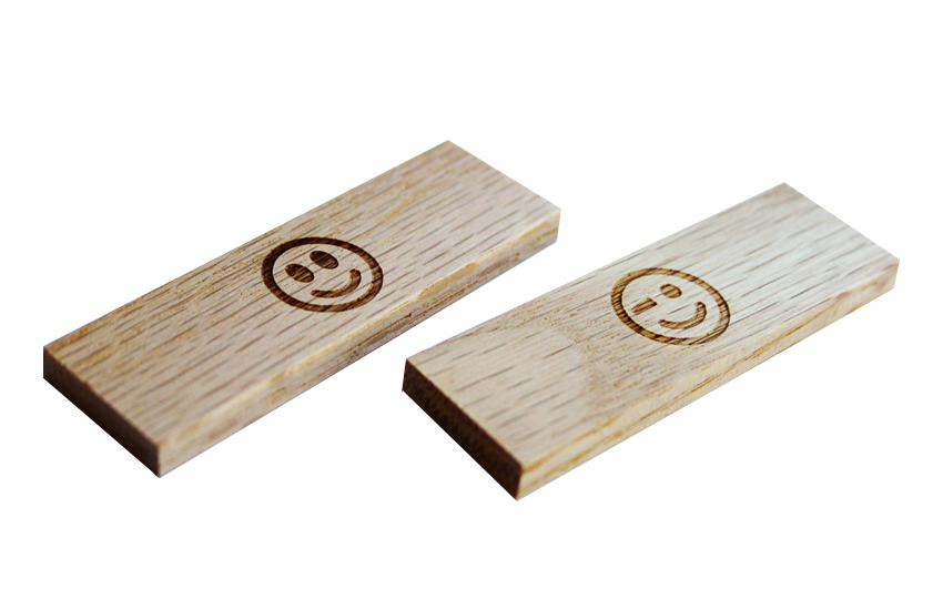 Two small wooden rectangular blocks with engraved smiley faces on a white background.